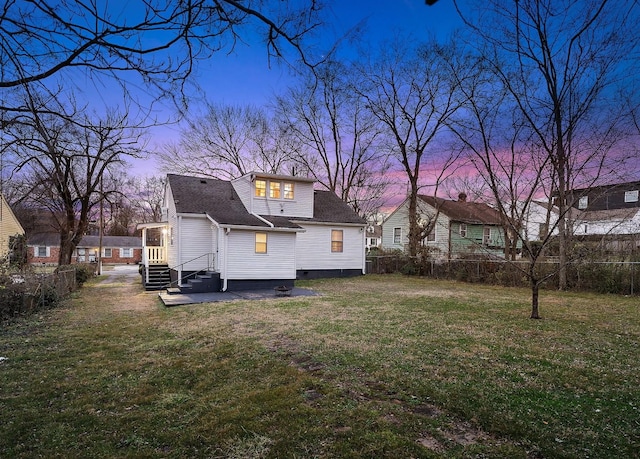 back house at dusk featuring a yard