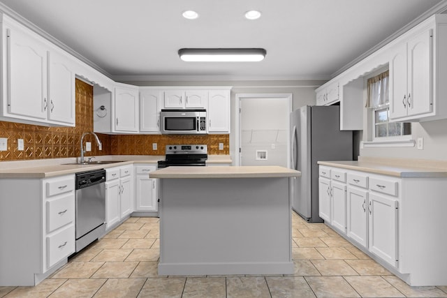 kitchen featuring white cabinetry, a center island, sink, crown molding, and appliances with stainless steel finishes