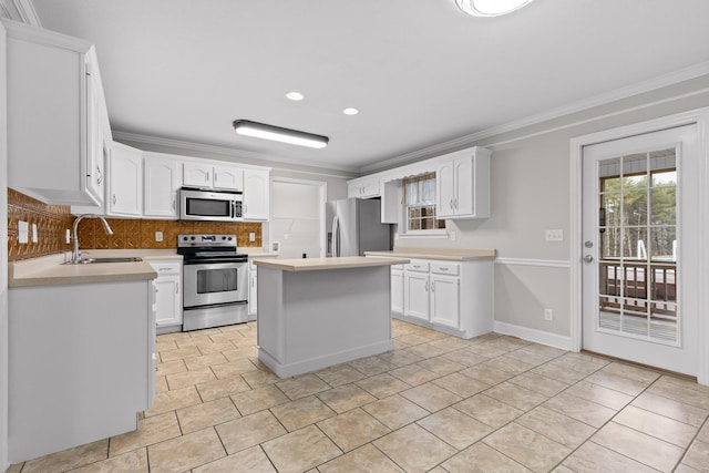 kitchen with a center island, white cabinets, crown molding, sink, and stainless steel appliances