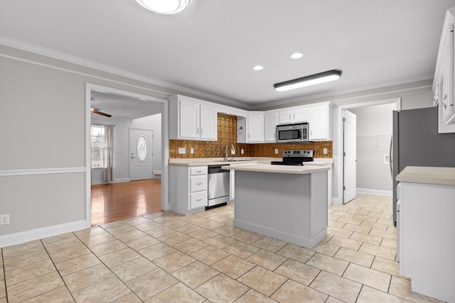 kitchen featuring appliances with stainless steel finishes, a center island, white cabinetry, and crown molding