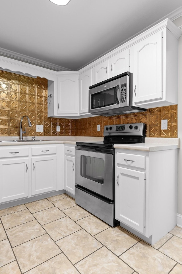 kitchen with sink, stainless steel appliances, light tile patterned floors, decorative backsplash, and white cabinets