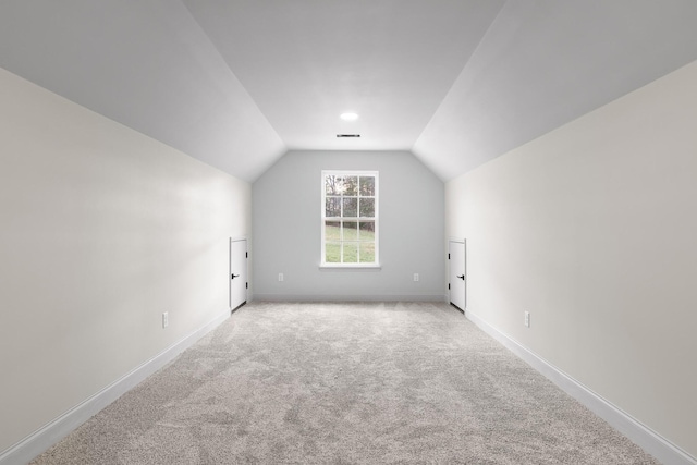 additional living space featuring light colored carpet and vaulted ceiling