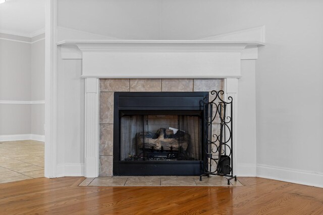 details with hardwood / wood-style floors, crown molding, and a tiled fireplace