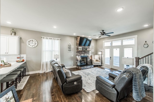 living room with a fireplace, a healthy amount of sunlight, ceiling fan, and dark wood-type flooring