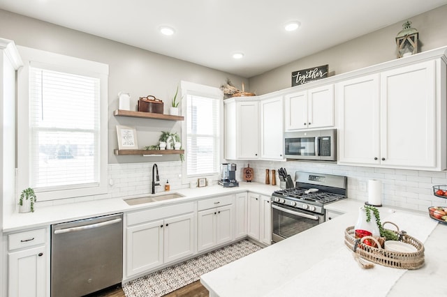 kitchen featuring decorative backsplash, white cabinetry, sink, and stainless steel appliances