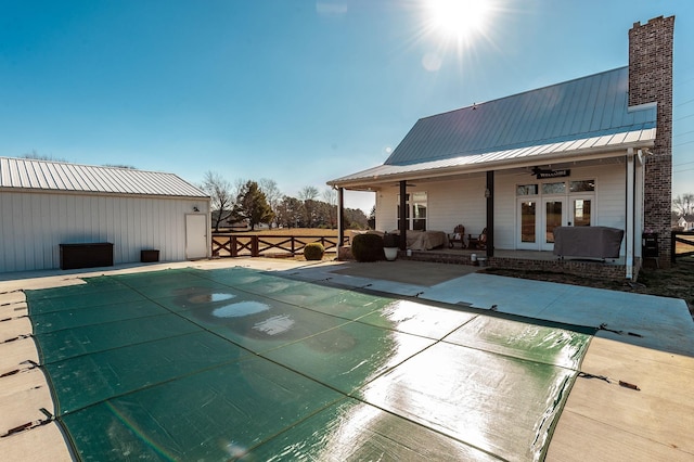 view of swimming pool featuring a patio area, ceiling fan, and french doors