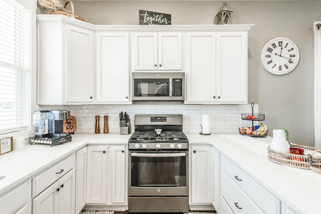 kitchen with white cabinets, stainless steel appliances, and tasteful backsplash