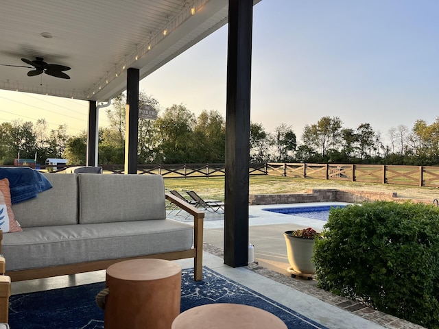 patio terrace at dusk featuring ceiling fan, a fenced in pool, and an outdoor living space