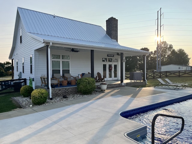 back house at dusk with french doors, ceiling fan, and a patio area