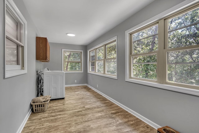 washroom with cabinets, hookup for a washing machine, and light hardwood / wood-style flooring