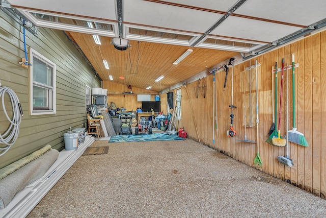 garage featuring a garage door opener and wooden walls