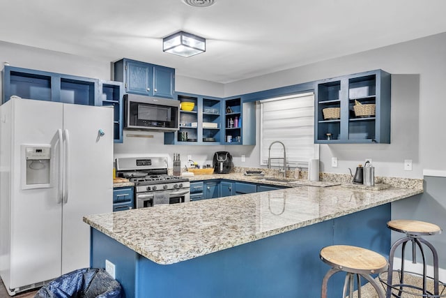 kitchen with blue cabinetry, stainless steel appliances, kitchen peninsula, and sink