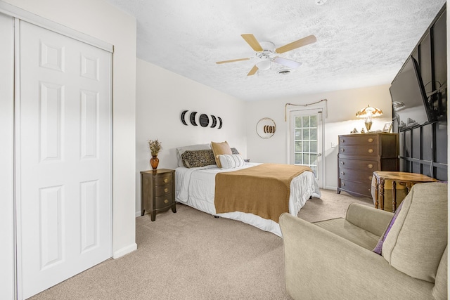 carpeted bedroom featuring ceiling fan, a closet, and a textured ceiling