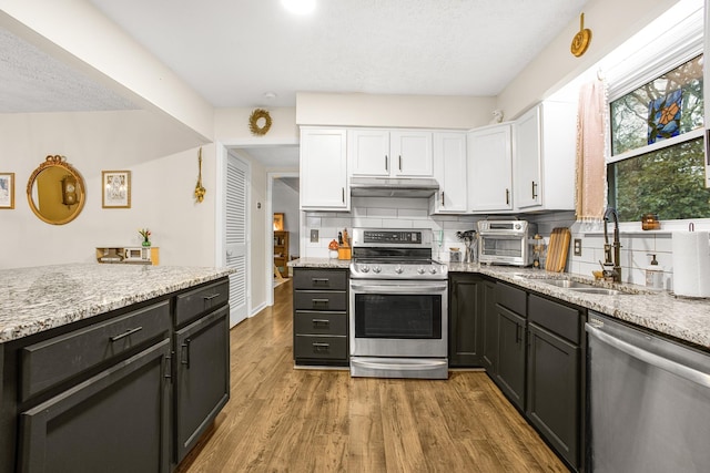 kitchen featuring light stone countertops, appliances with stainless steel finishes, backsplash, and white cabinetry