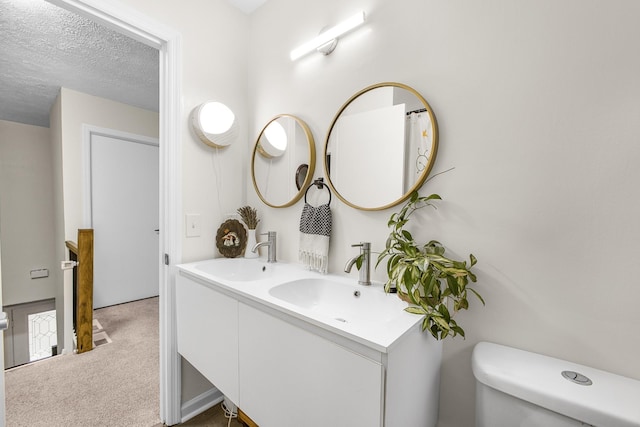 bathroom featuring vanity, a textured ceiling, and toilet