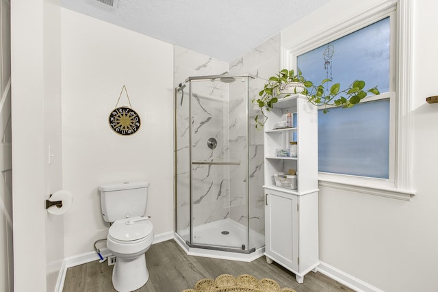 bathroom featuring toilet, a shower with shower door, a textured ceiling, and wood-type flooring