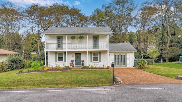 view of front of property with a front lawn, a balcony, and french doors