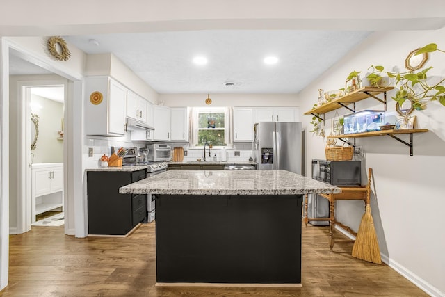 kitchen featuring a center island, white cabinets, sink, light stone countertops, and stainless steel appliances