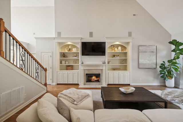 living room featuring hardwood / wood-style flooring, built in shelves, and high vaulted ceiling