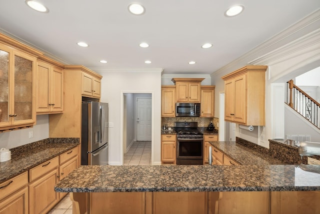 kitchen with kitchen peninsula, dark stone countertops, light tile patterned floors, and appliances with stainless steel finishes