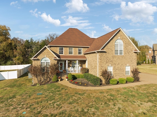 front facade featuring covered porch and a front lawn