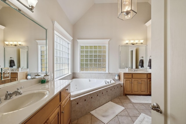 bathroom with tile patterned floors, tiled bath, vanity, and vaulted ceiling