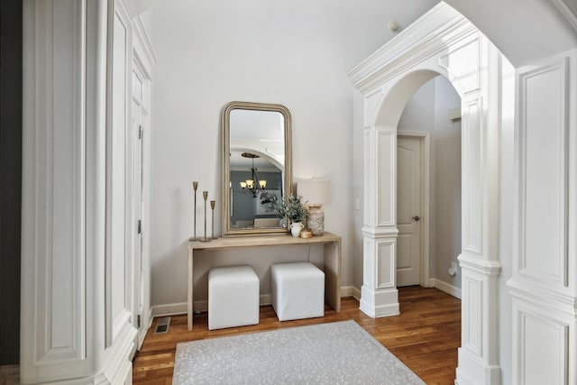 hall with decorative columns, a chandelier, and dark wood-type flooring