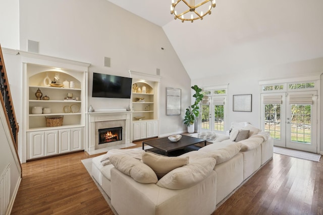 living room with french doors, hardwood / wood-style floors, built in features, and a notable chandelier