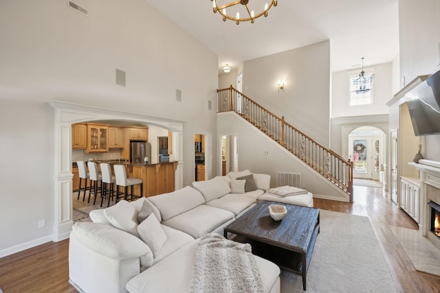 living room with a tile fireplace, wood-type flooring, a high ceiling, and an inviting chandelier