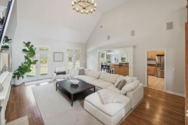 living room with a chandelier, french doors, dark wood-type flooring, and a high ceiling