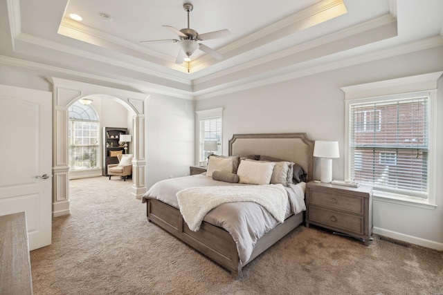 carpeted bedroom featuring a raised ceiling, multiple windows, and ceiling fan