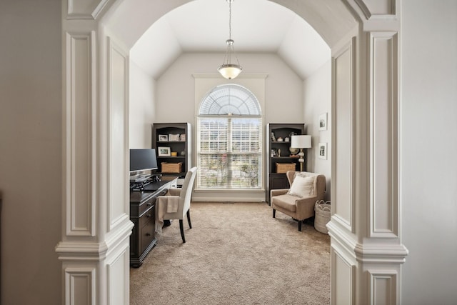 carpeted home office featuring decorative columns and lofted ceiling