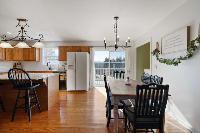 dining area with an inviting chandelier, light hardwood / wood-style flooring, and sink