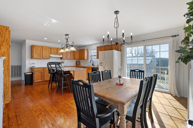 dining space featuring a notable chandelier, light hardwood / wood-style flooring, and sink