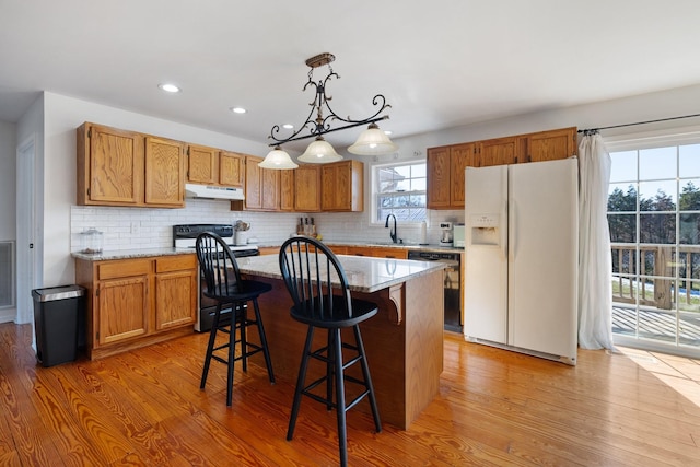 kitchen featuring dishwasher, hanging light fixtures, a kitchen island, electric stove, and white refrigerator with ice dispenser