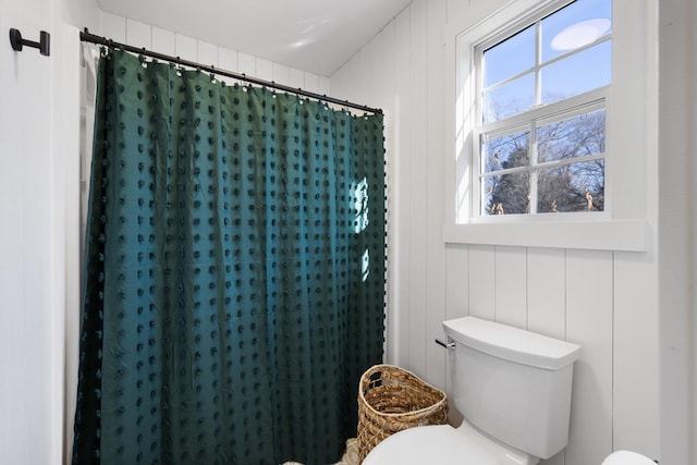 bathroom featuring toilet, walk in shower, and wood walls