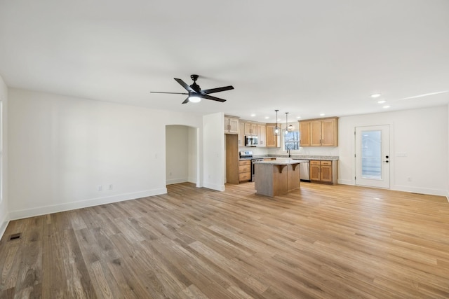 kitchen featuring appliances with stainless steel finishes, ceiling fan, decorative light fixtures, light hardwood / wood-style flooring, and a kitchen island