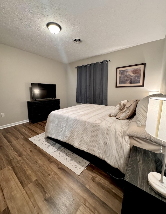 bedroom featuring dark hardwood / wood-style flooring and a textured ceiling