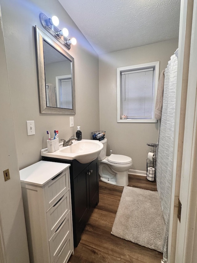 bathroom with hardwood / wood-style floors, vanity, toilet, and a textured ceiling