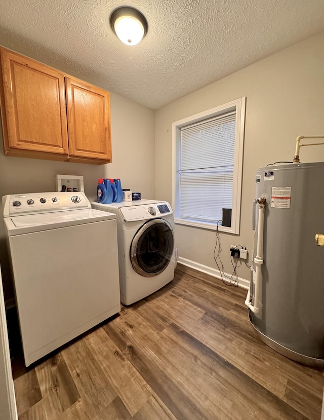 laundry area featuring cabinets, electric water heater, a textured ceiling, independent washer and dryer, and dark hardwood / wood-style floors