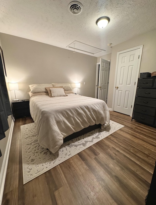 bedroom with a textured ceiling and dark wood-type flooring