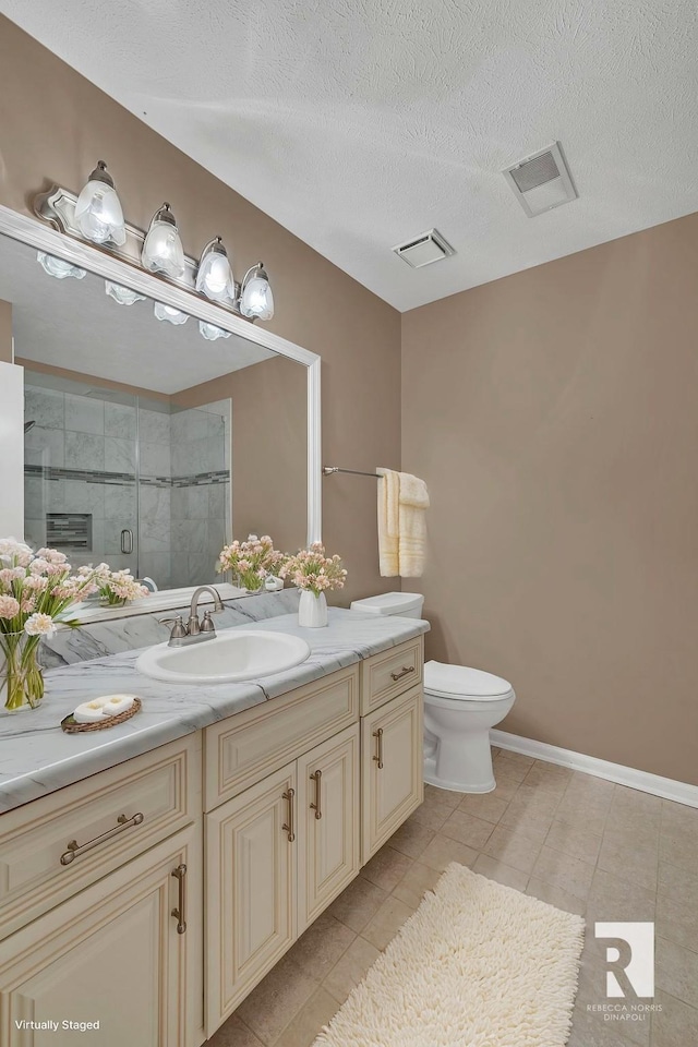 bathroom with toilet, a shower with shower door, a textured ceiling, vanity, and tile patterned flooring