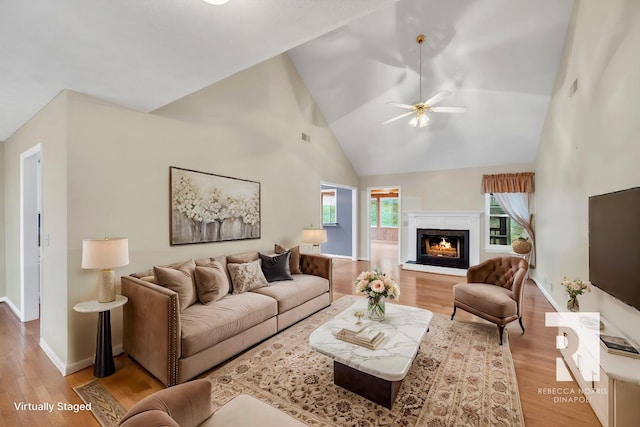 living room with ceiling fan, high vaulted ceiling, and light hardwood / wood-style floors