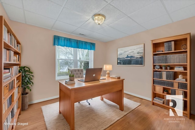 home office with light hardwood / wood-style flooring and a drop ceiling