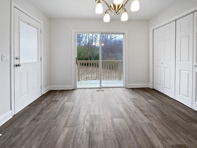 unfurnished dining area with a notable chandelier and dark wood-type flooring