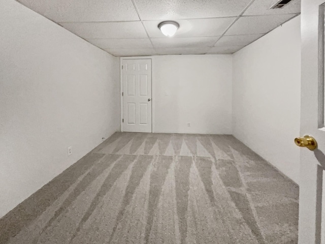 carpeted spare room featuring a drop ceiling