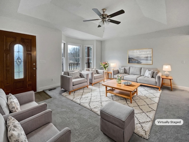 living room featuring a tray ceiling, ceiling fan, and light colored carpet