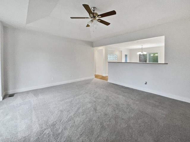 carpeted spare room featuring ceiling fan with notable chandelier and a raised ceiling