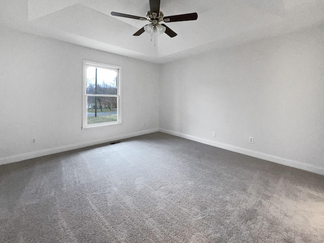 carpeted empty room featuring ceiling fan and a tray ceiling