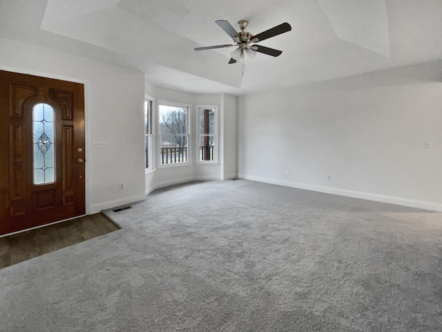 carpeted foyer entrance featuring a tray ceiling and ceiling fan